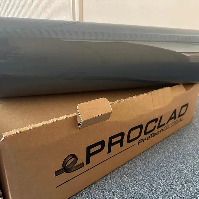 Grå folie fra Proclad liggende oppå en åpen eske merket med ProTech Global-logo.