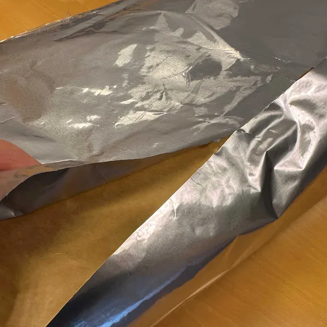 Lagvis folie med blank overflate brettes delvis til side for å vise brunt innvendig lag.