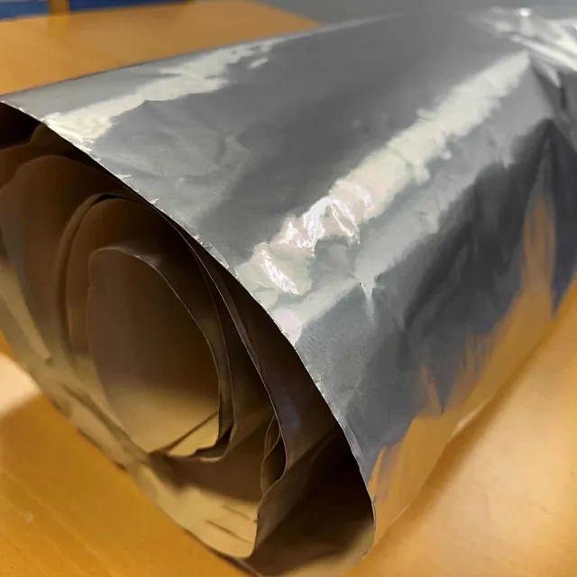 Grå folie rullet sammen med synlige, ovale innsnitt i materialet ytterst på rullen.