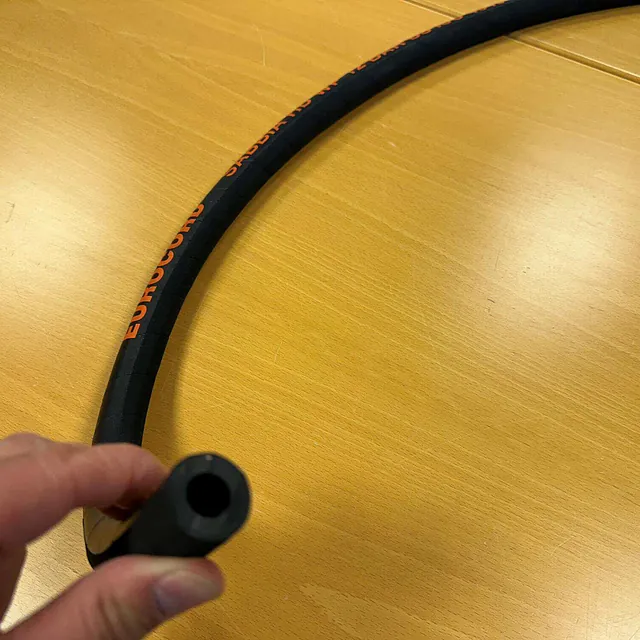 En hånd holder en fleksibel gummislange med teksten "EUROCORD SABBIA" synlig langs siden.