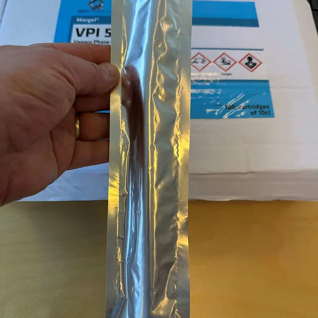 Hånd holder én patron av VPI 580 foran esken med etiketten i bakgrunnen.