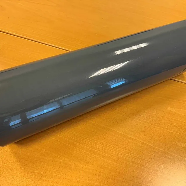 Rull med grå folie liggende på et bord med treoverflate.