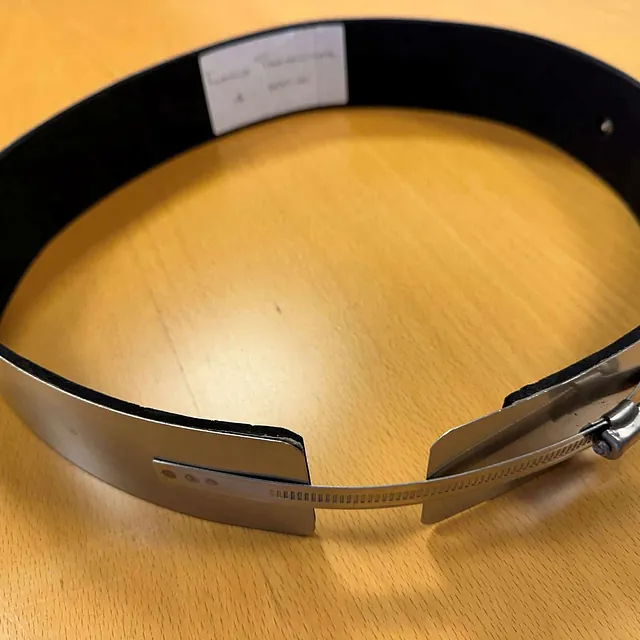 Nærbilde av en metallbåndvarmer med sort innside og justerbar skruklemme.